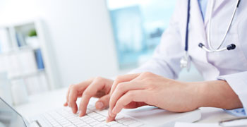 Healthcare professional writing a report on a computer